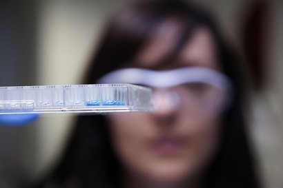 Close up view of female researcher wearing protective glasses and gloves working in laboratory.